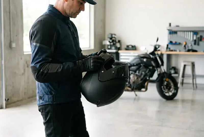 Motard choisissant son casque dans un atelier moto