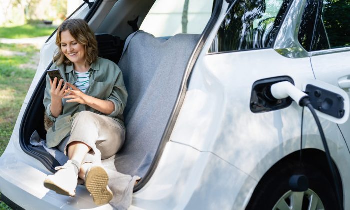 Femme heureuse du choix de sa voiture électrisue