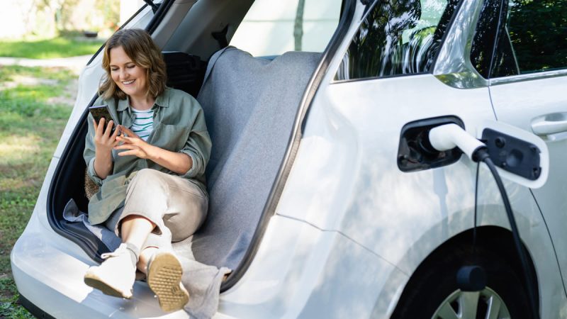 Femme heureuse du choix de sa voiture électrisue